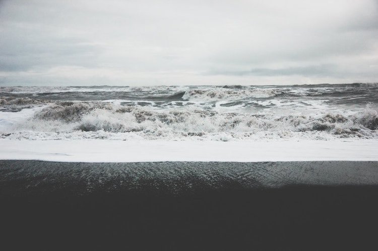waves breaking on a black sand beach on a cloudy day